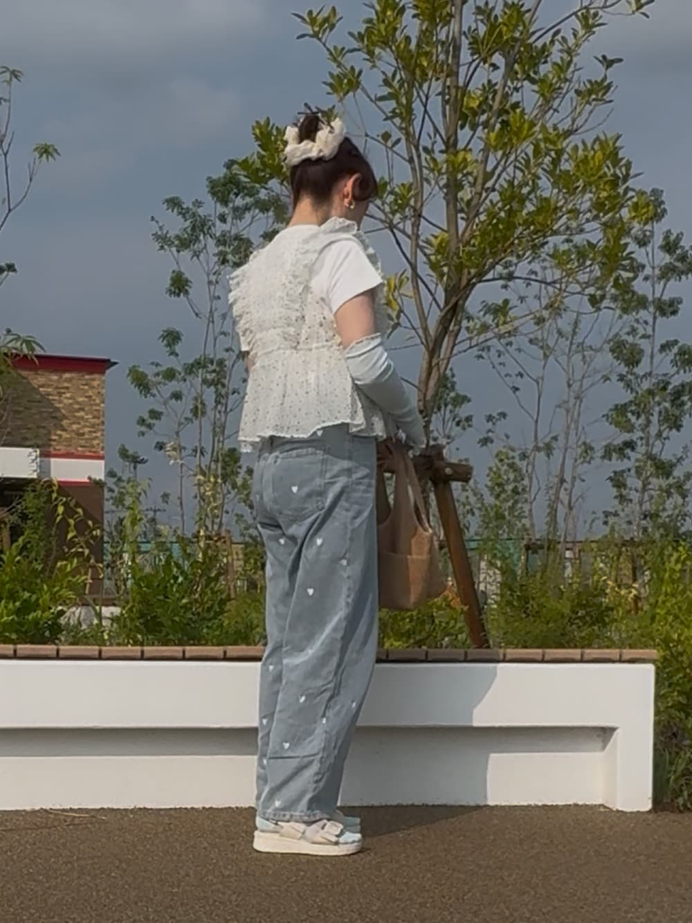 ホワイト系のベスト、ブルー系のデニムパンツ、ブラウン系のトートバッグを着用したレディースの夏コーディネートの2枚目の写真