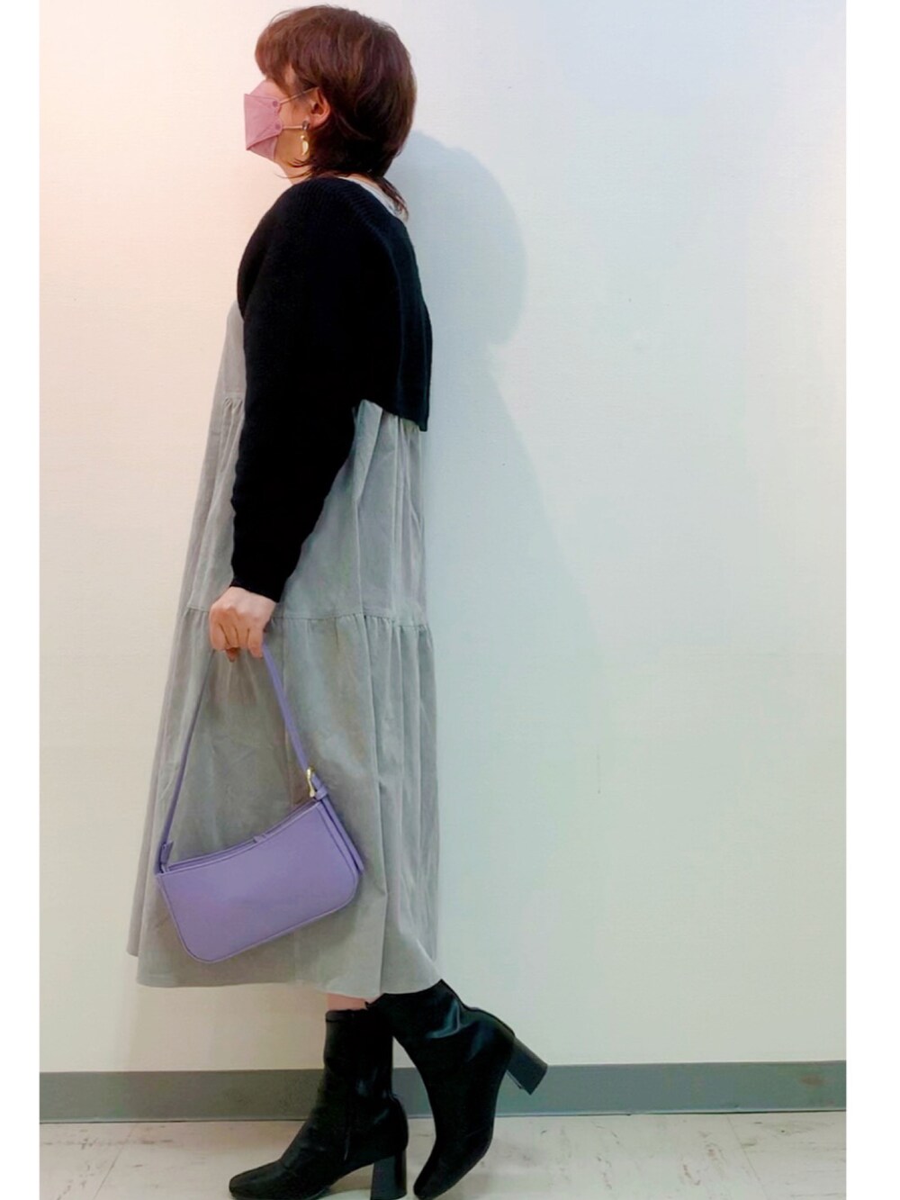 パープル系のハンドバッグ、ブラック系のブーツ、グレー系のワンピースを着用したレディースの秋コーディネートの2枚目の写真