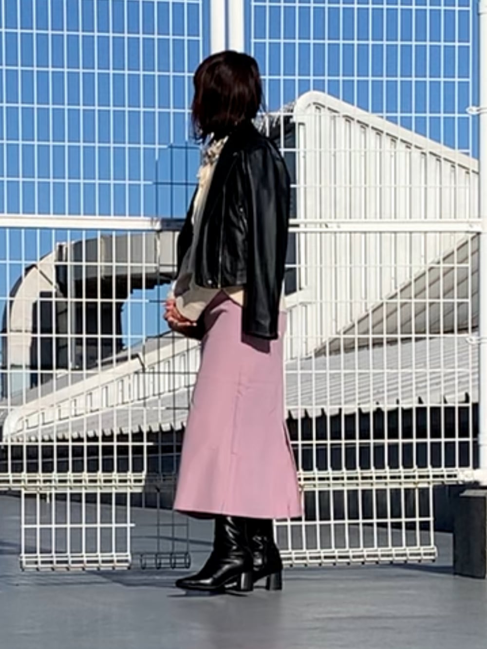 ベージュ系のショルダーバッグ、ピンク系のスカート、ブラック系のライダースジャケットを着用したレディースの冬コーディネートの2枚目の写真