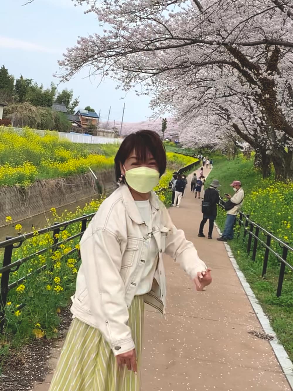 イエロー系のスカート、ブラック系のドレスシューズ、ホワイト系のデニムジャケットを着用したレディースの春コーディネートの3枚目の写真