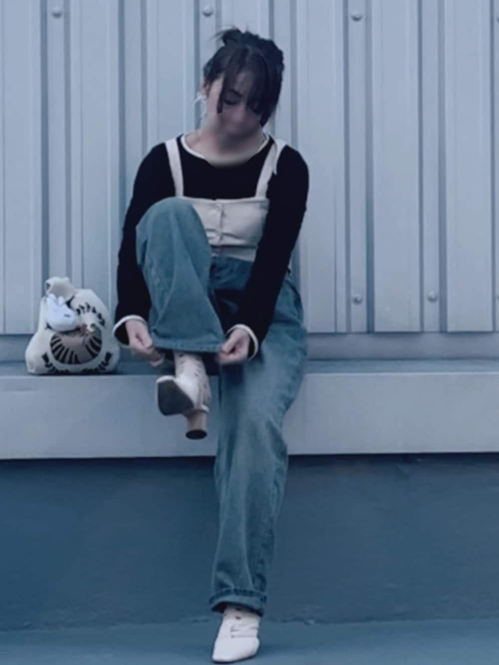 ベージュ系のパンプス、ブルー系のデニムパンツ、ホワイト系のショルダーバッグを着用したレディースの春コーディネートの2枚目の写真