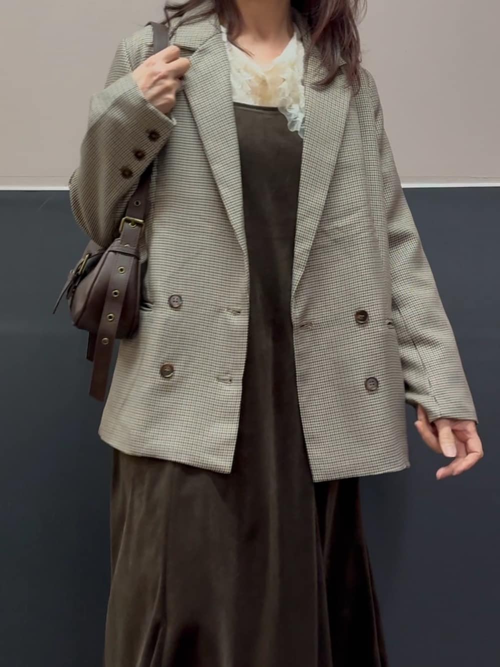 ブラウン系のショルダーバッグ、ベージュ系のテーラードジャケット、ホワイト系のブーツを着用したレディースの冬コーディネートの2枚目の写真