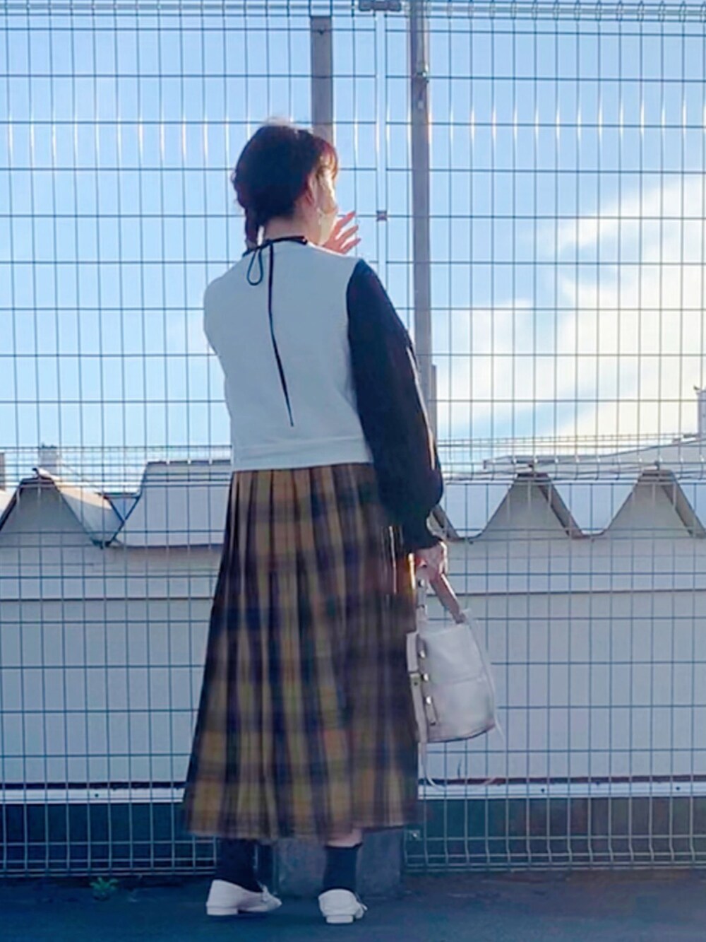 ホワイト系のベスト、イエロー系のスカート、ベージュ系のバッグを着用したレディースの秋コーディネートの2枚目の写真