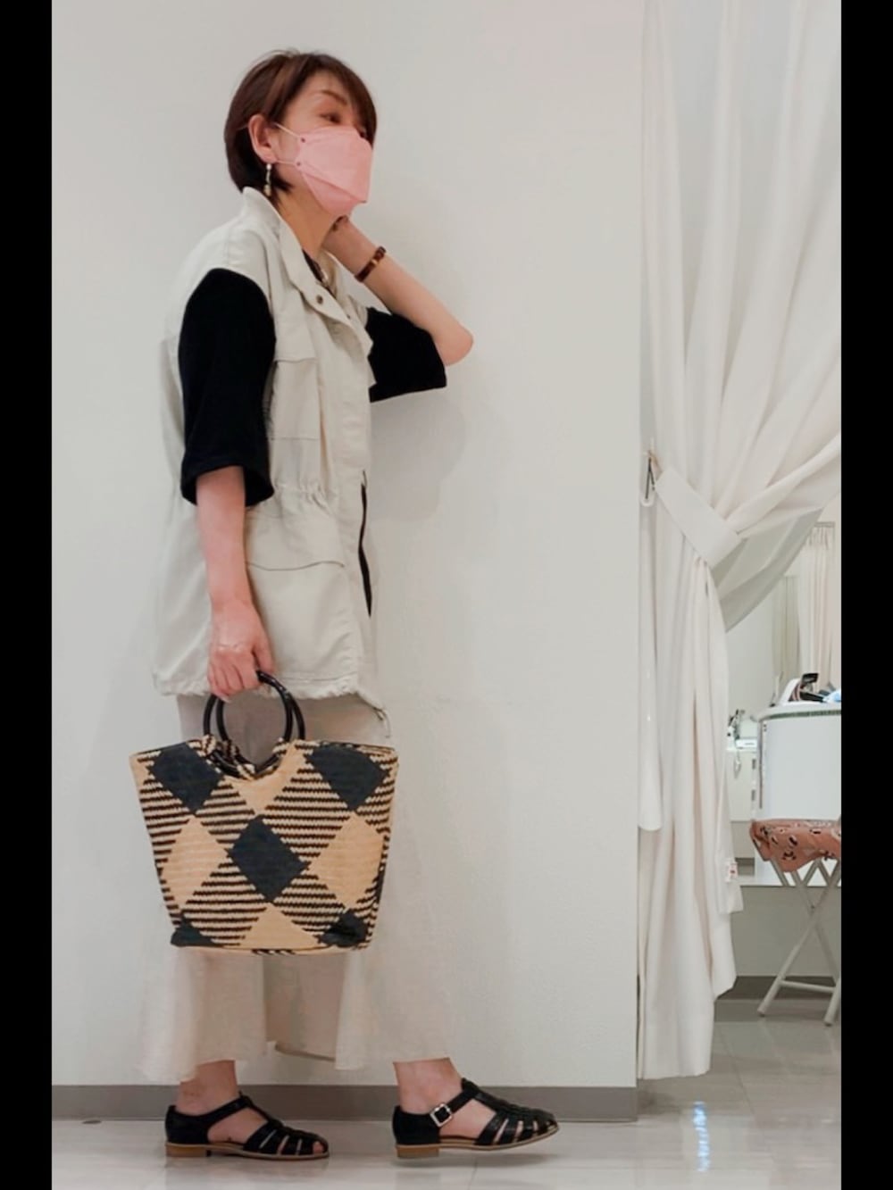 ベージュ系のベスト、ホワイト系のスカート、ブラック系のサンダルを着用したレディースの夏コーディネートの2枚目の写真