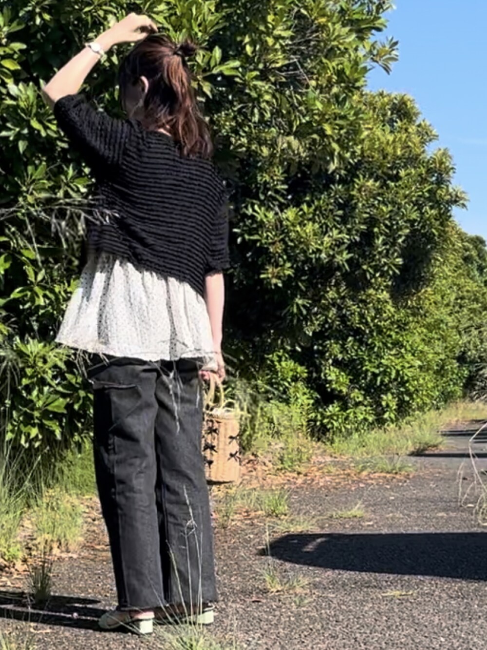 ホワイト系のキャミソール、ベージュ系のかごバッグ、グリーン系のサンダルを着用したレディースの夏コーディネートの2枚目の写真