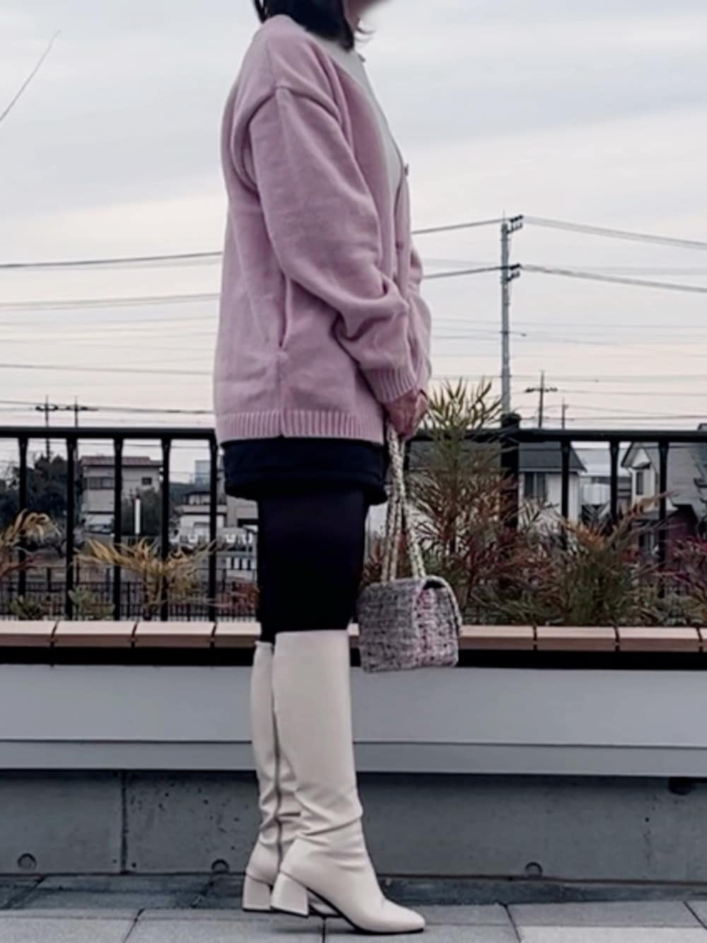 ピンク系のカーディガン/ボレロ、ブラック系のスカート、ホワイト系のショルダーバッグを着用したレディースの冬コーディネートの2枚目の写真