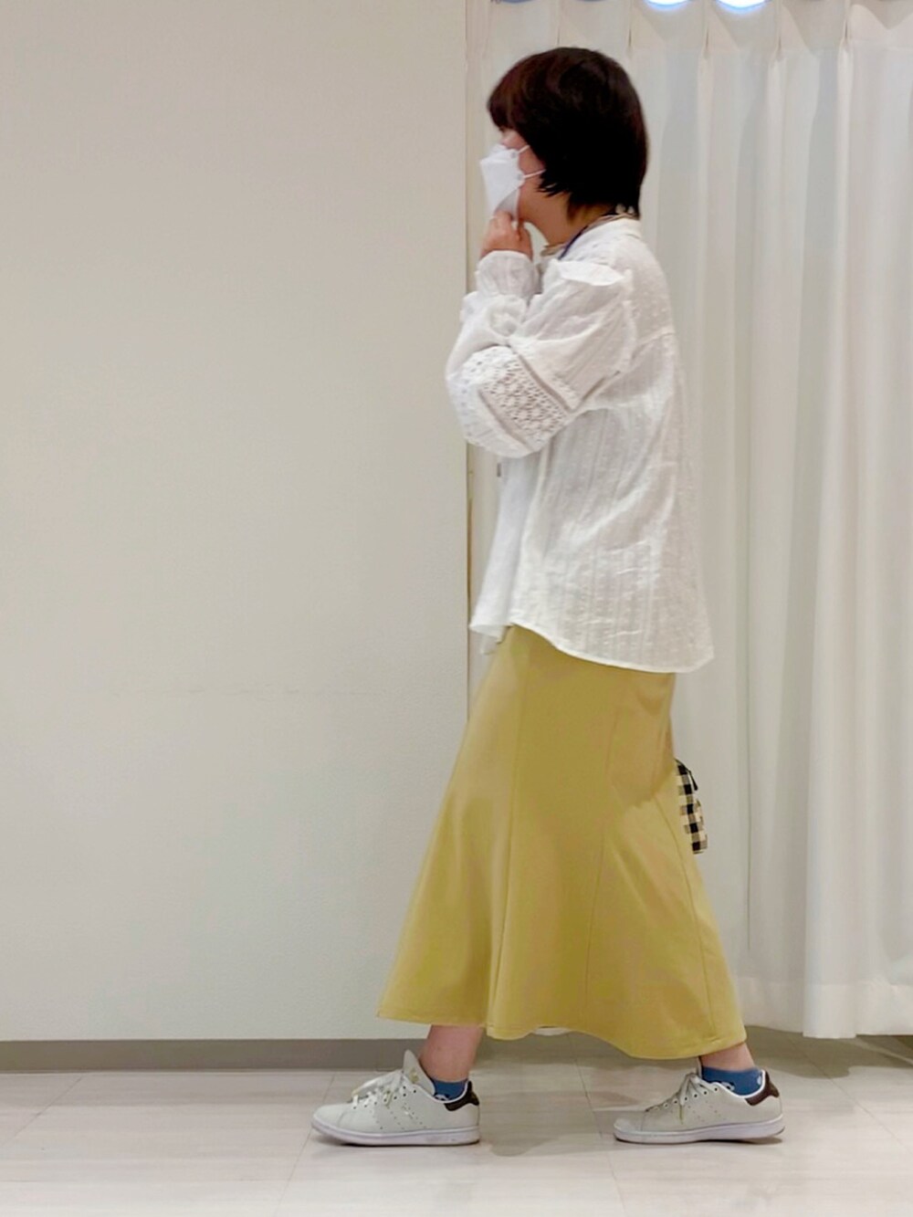 ブラック系のハンドバッグ、ホワイト系のシャツ/ブラウス、イエロー系のスカートを着用したレディースの春コーディネートの2枚目の写真
