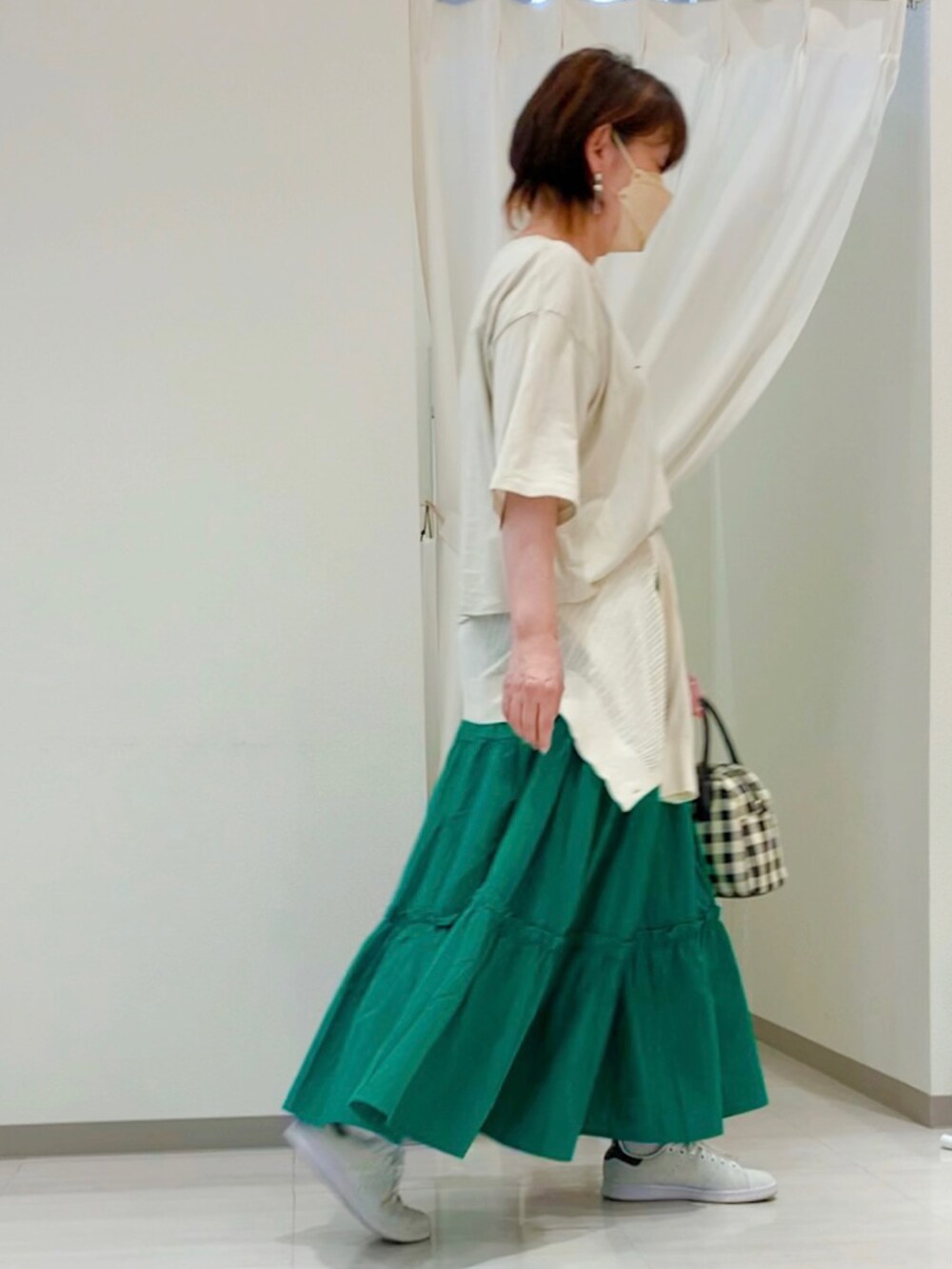 ベージュ系のTシャツ/カットソー、ブラック系のハンドバッグ、グリーン系のスカートを着用したレディースの春コーディネートの2枚目の写真