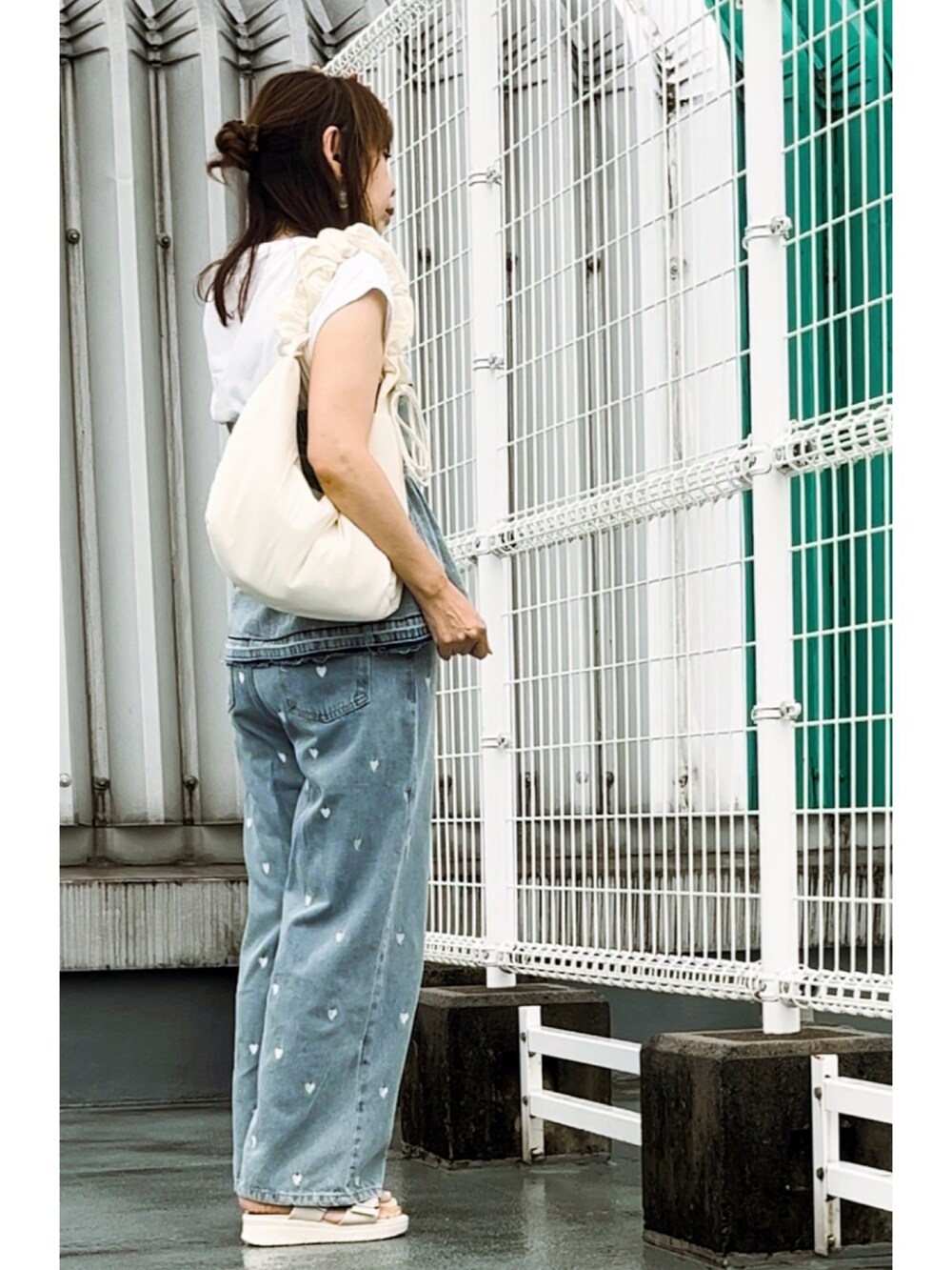 ブルー系のチューブトップ、ブルー系のデニムパンツ、ホワイト系のサンダルを着用したレディースの秋コーディネートの2枚目の写真