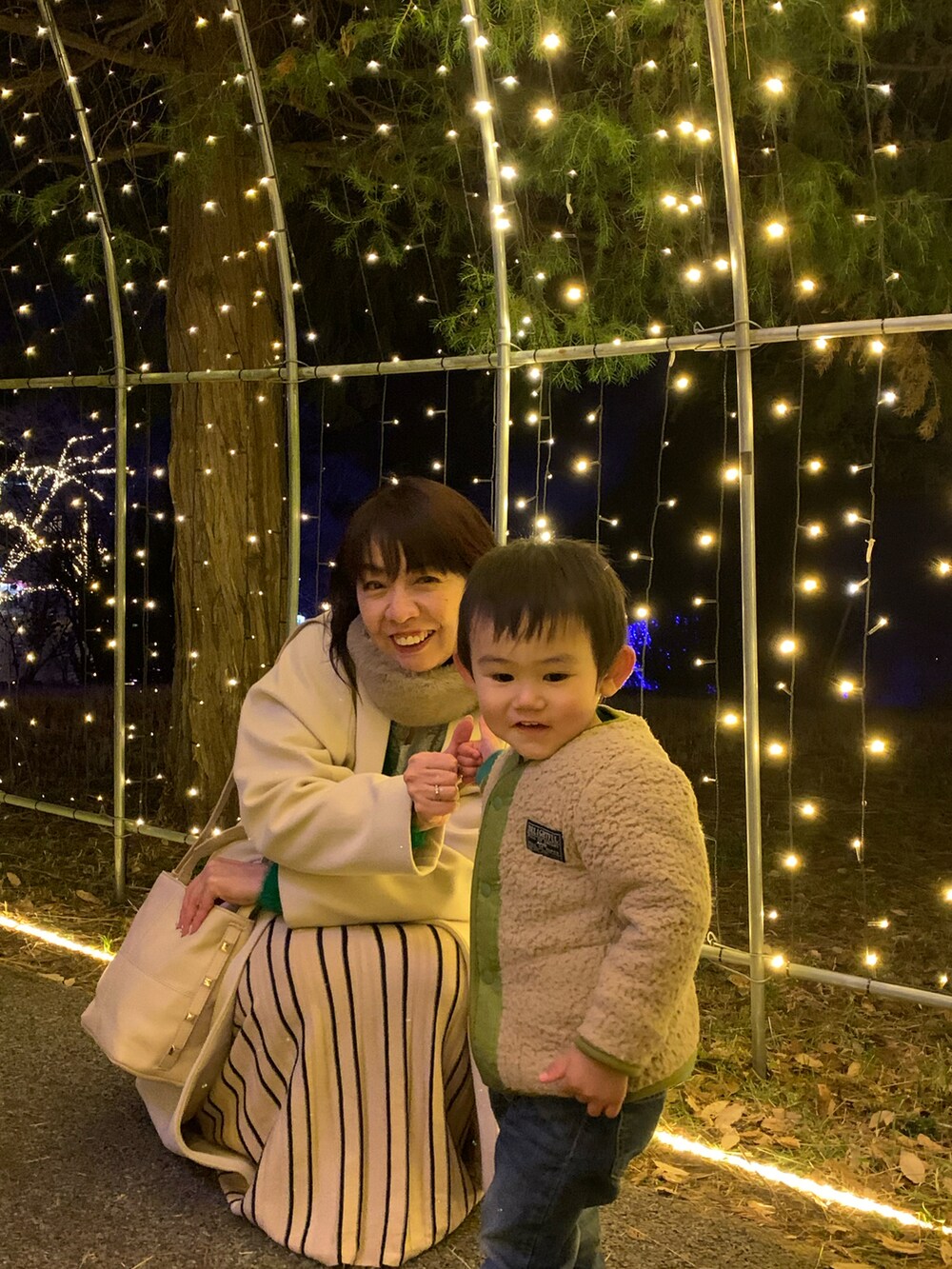 グリーン系のカーディガン/ボレロ、ベージュ系のスカート、ホワイト系のブーツを着用したレディースの冬コーディネートの3枚目の写真