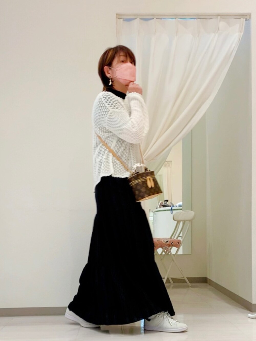 ホワイト系のニット/セーター、ブラウン系のボディバッグ/ウエストポーチ、ブラック系のスカートを着用したレディースの春コーディネートの2枚目の写真