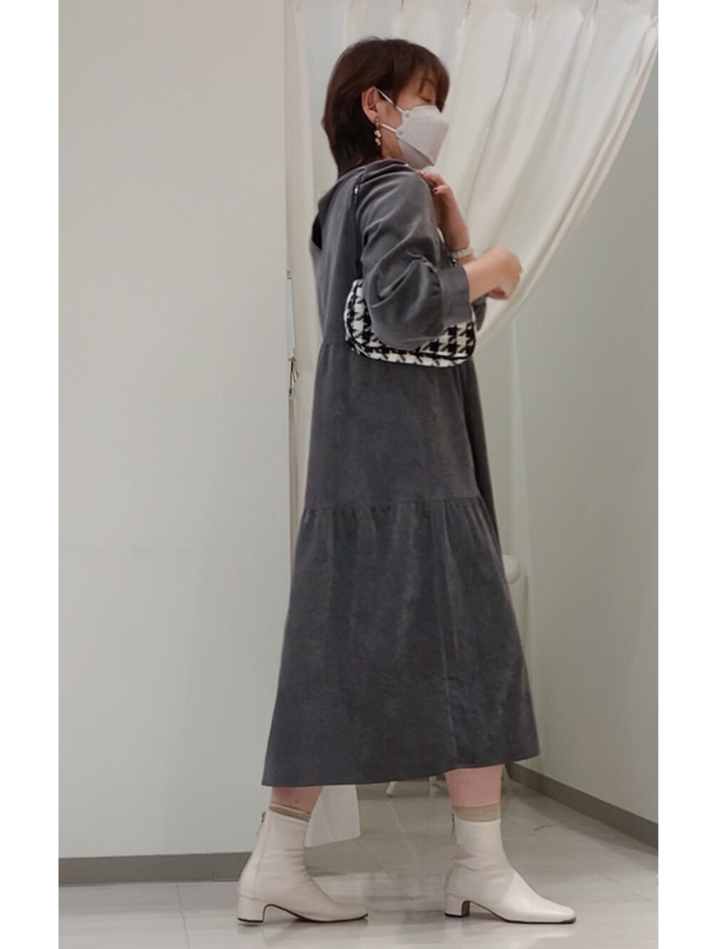 グレー系のワンピース、ブラック系のハンドバッグ、ホワイト系のブーツを着用したレディースの秋コーディネートの3枚目の写真