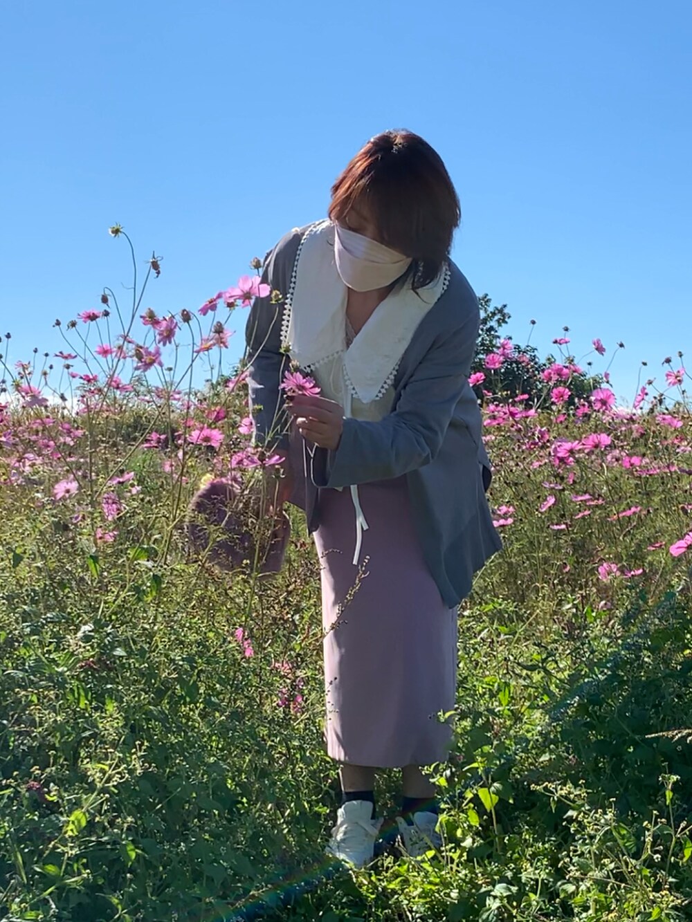 グレー系のカーディガン/ボレロ、ピンク系のスカート、ホワイト系のスニーカーを着用したレディースの秋コーディネートの2枚目の写真