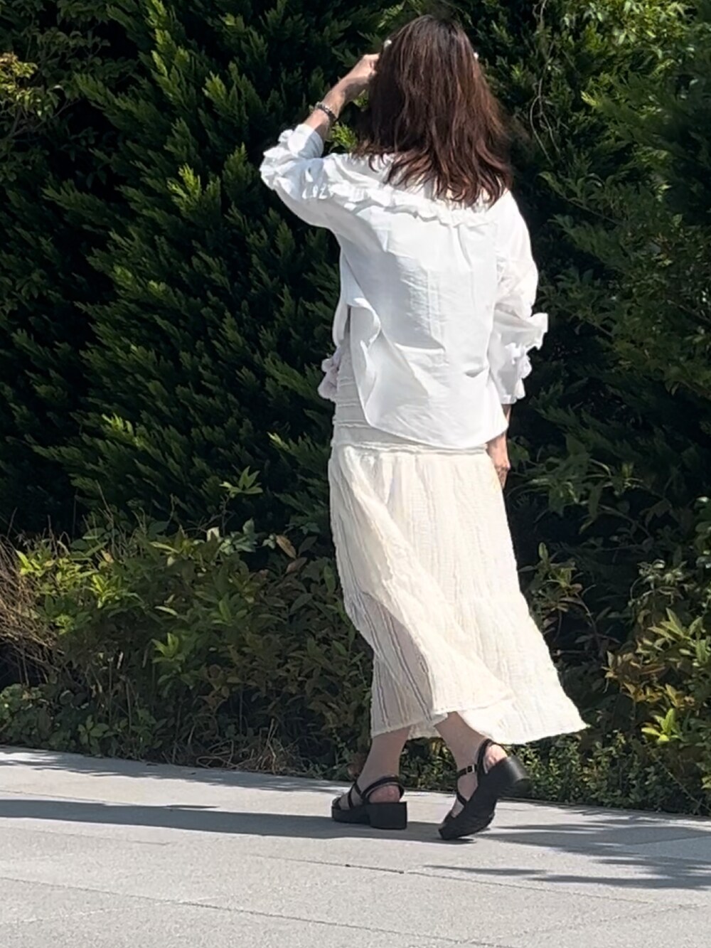 ホワイト系のスカート、ブラック系のサンダル、ブラック系のトートバッグを着用したレディースの秋コーディネートの2枚目の写真