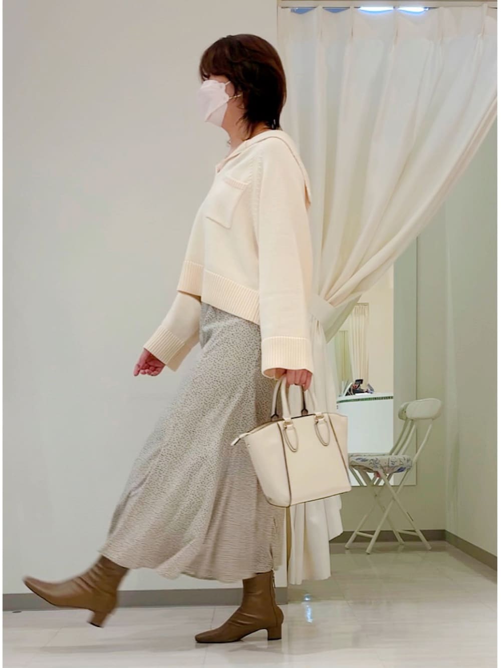 ホワイト系のニット/セーター、ベージュ系のスカート、ブラウン系のブーツを着用したレディースの秋コーディネートの4枚目の写真