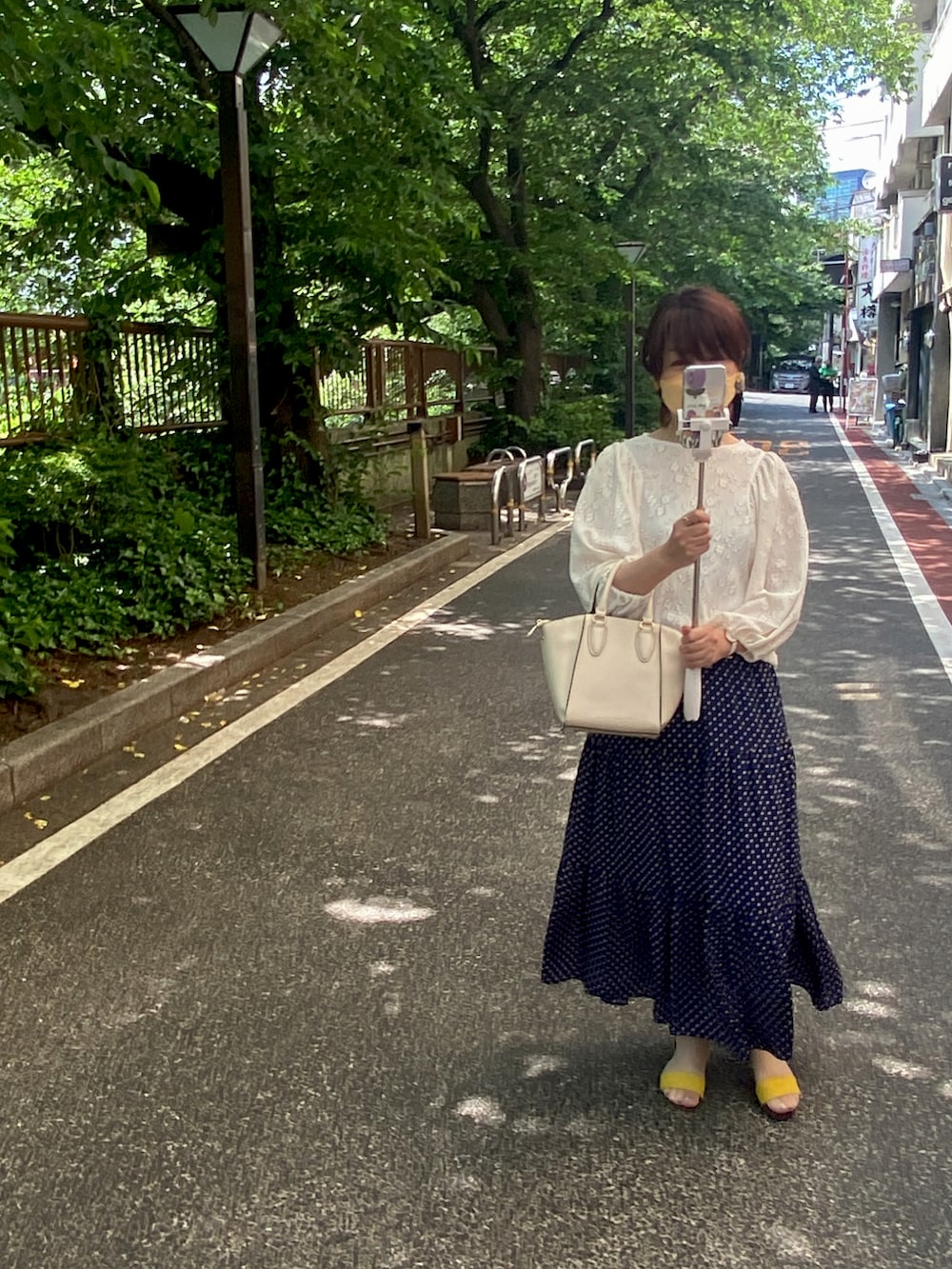 ブルー系のスカート、ホワイト系のショルダーバッグ、ホワイト系のシャツ/ブラウスを着用したレディースの春コーディネートの2枚目の写真