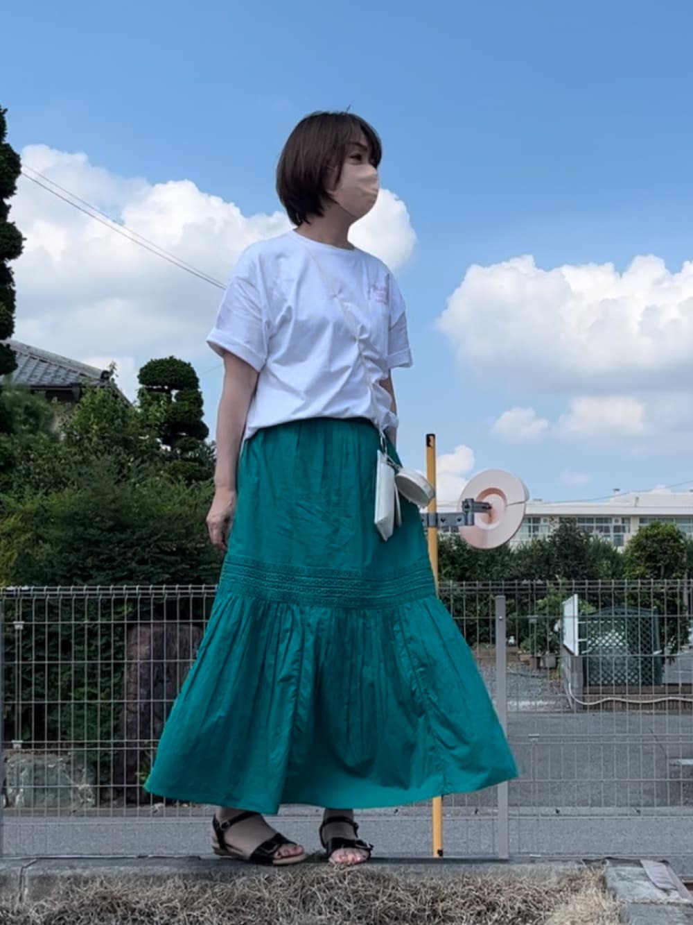 グリーン系のスカート、ホワイト系のチュニック、ホワイト系のボディバッグ/ウエストポーチを着用したレディースの夏コーディネートの4枚目の写真