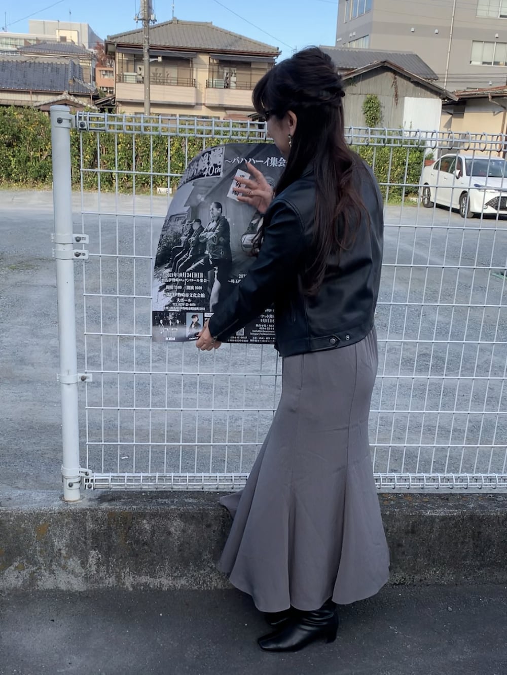 ブラック系のライダースジャケット、グレー系のスカート、ブラウン系のバッグを着用したレディースの秋コーディネートの2枚目の写真