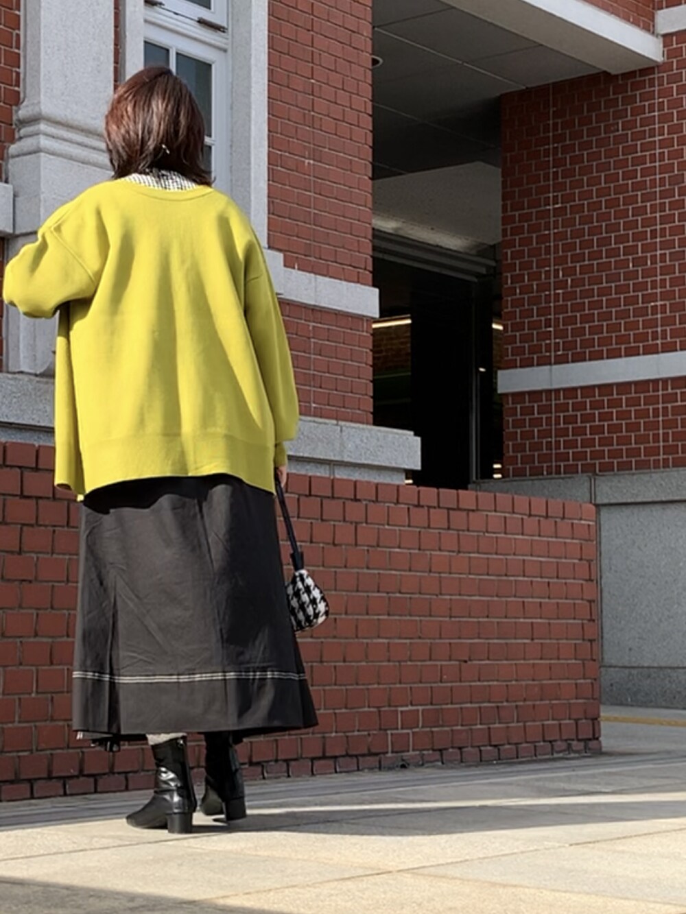 ブラック系のスカート、ブラック系のブーツ、ブラック系のシャツ/ブラウスを着用したレディースの秋コーディネートの2枚目の写真