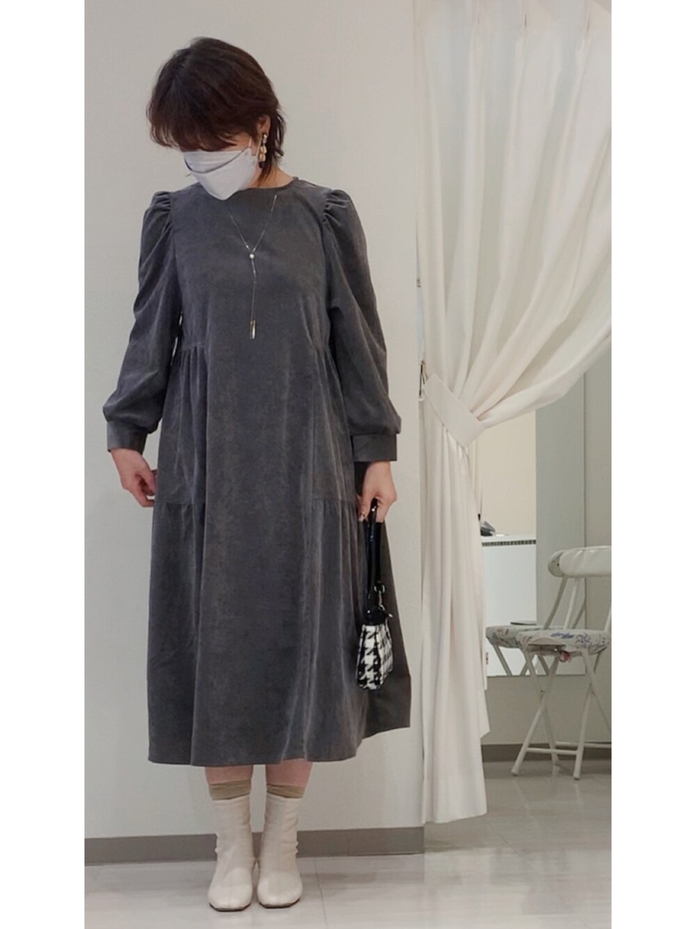 グレー系のワンピース、ブラック系のハンドバッグ、ホワイト系のブーツを着用したレディースの秋コーディネートの2枚目の写真