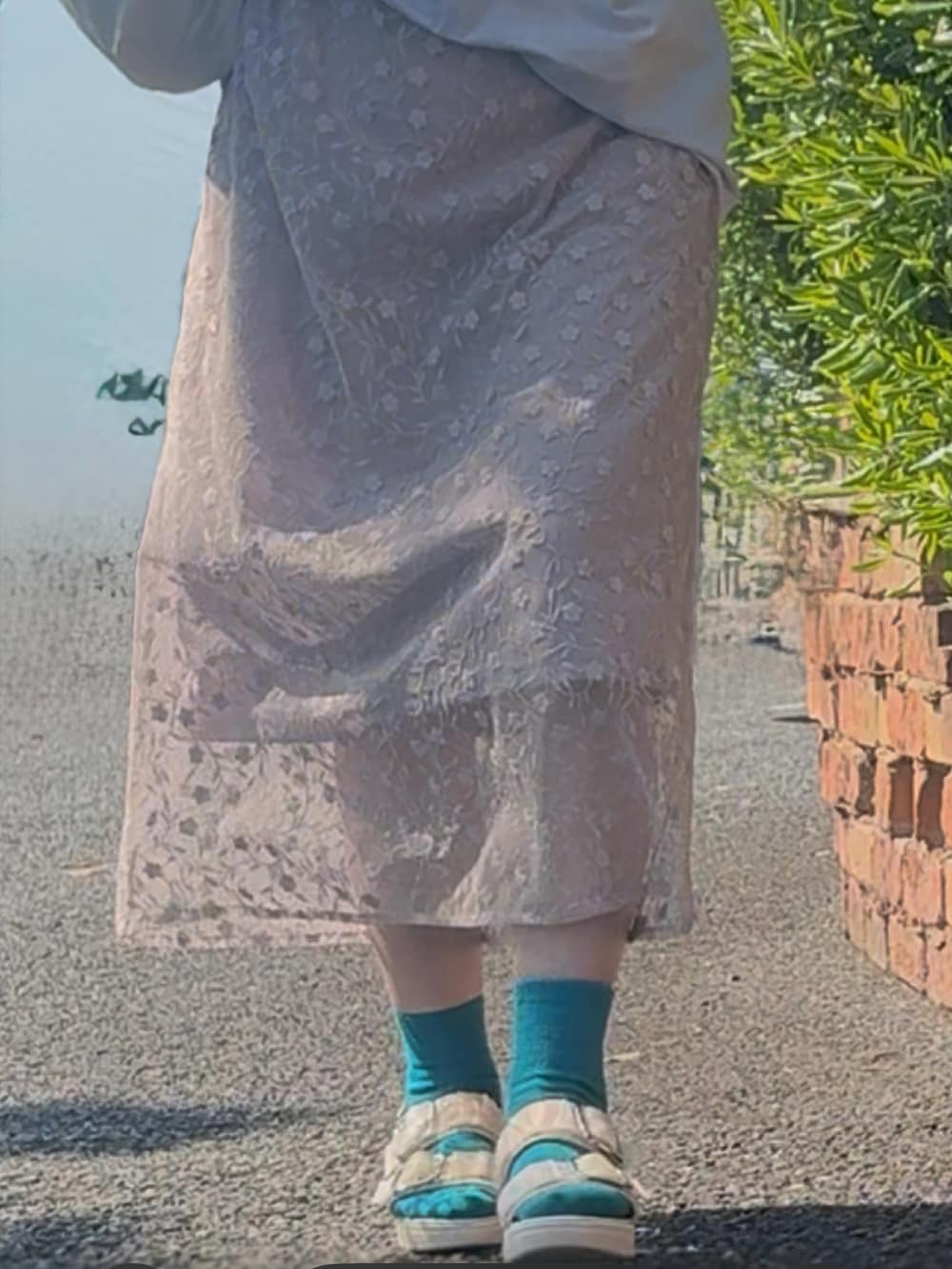 ピンク系のスカート、ブルー系のTシャツ/カットソー、ホワイト系のサンダルを着用したレディースの春コーディネートの3枚目の写真