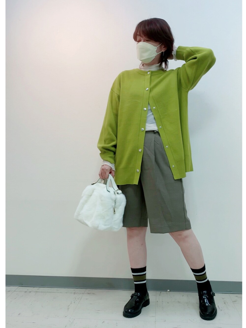 グリーン系のカーディガン/ボレロ、ブラック系のローファー、ホワイト系のバッグを着用したレディースの秋コーディネートの3枚目の写真