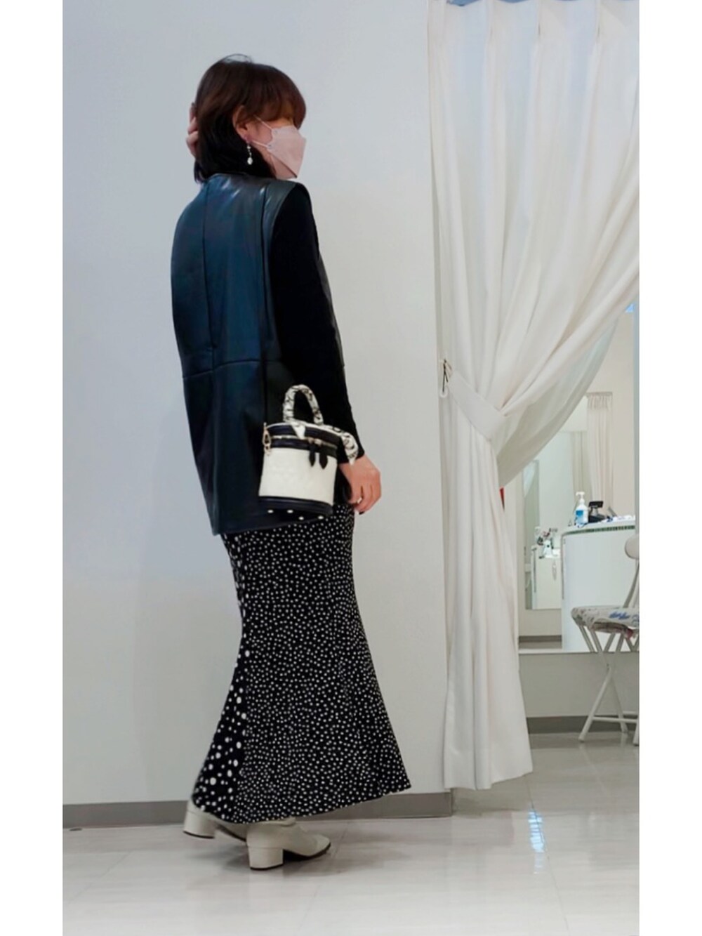 ホワイト系のショルダーバッグ、ブラック系のベスト、ブラック系のスカートを着用したレディースの冬コーディネートの3枚目の写真