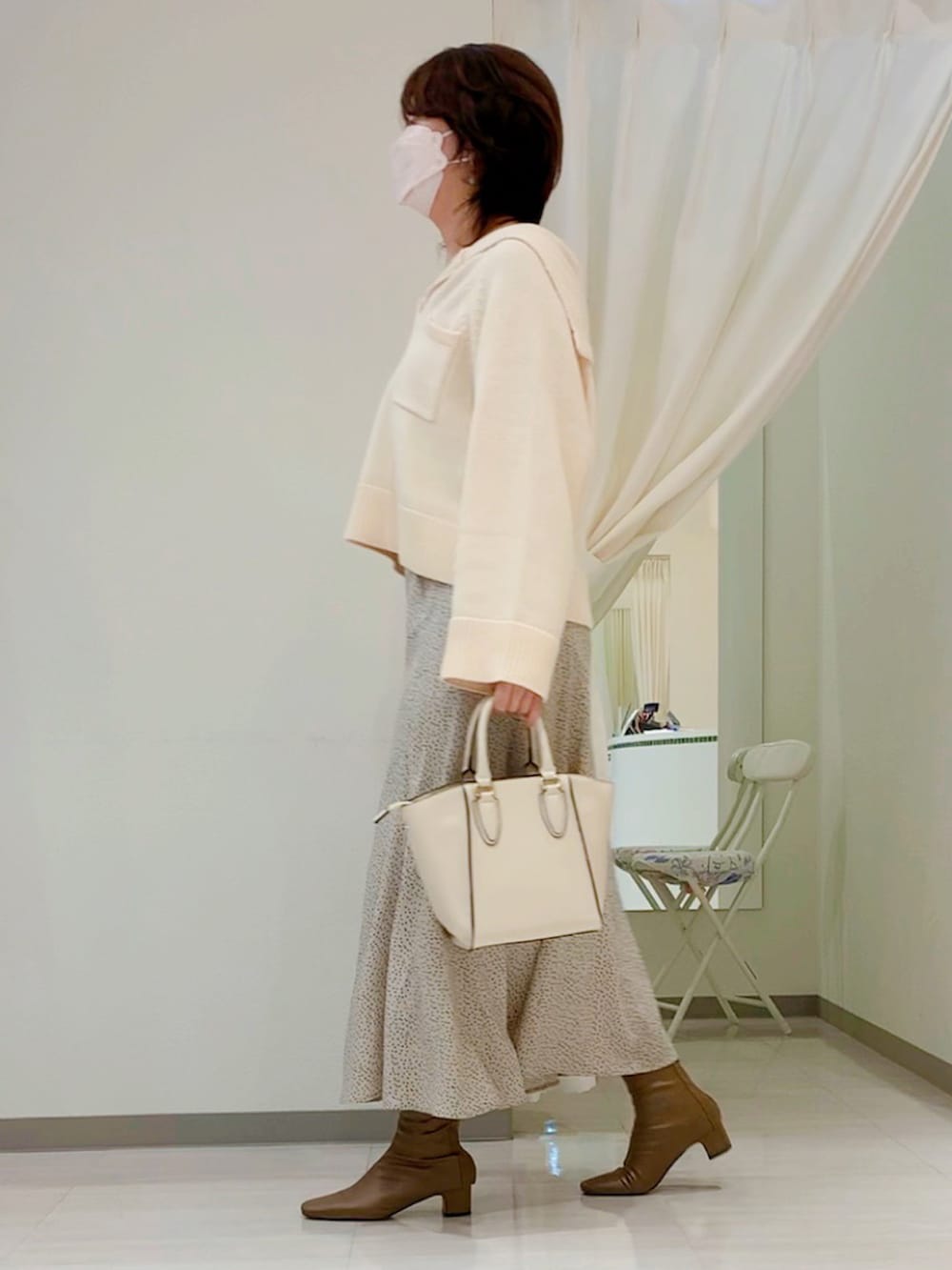 ホワイト系のニット/セーター、ベージュ系のスカート、ブラウン系のブーツを着用したレディースの秋コーディネートの2枚目の写真