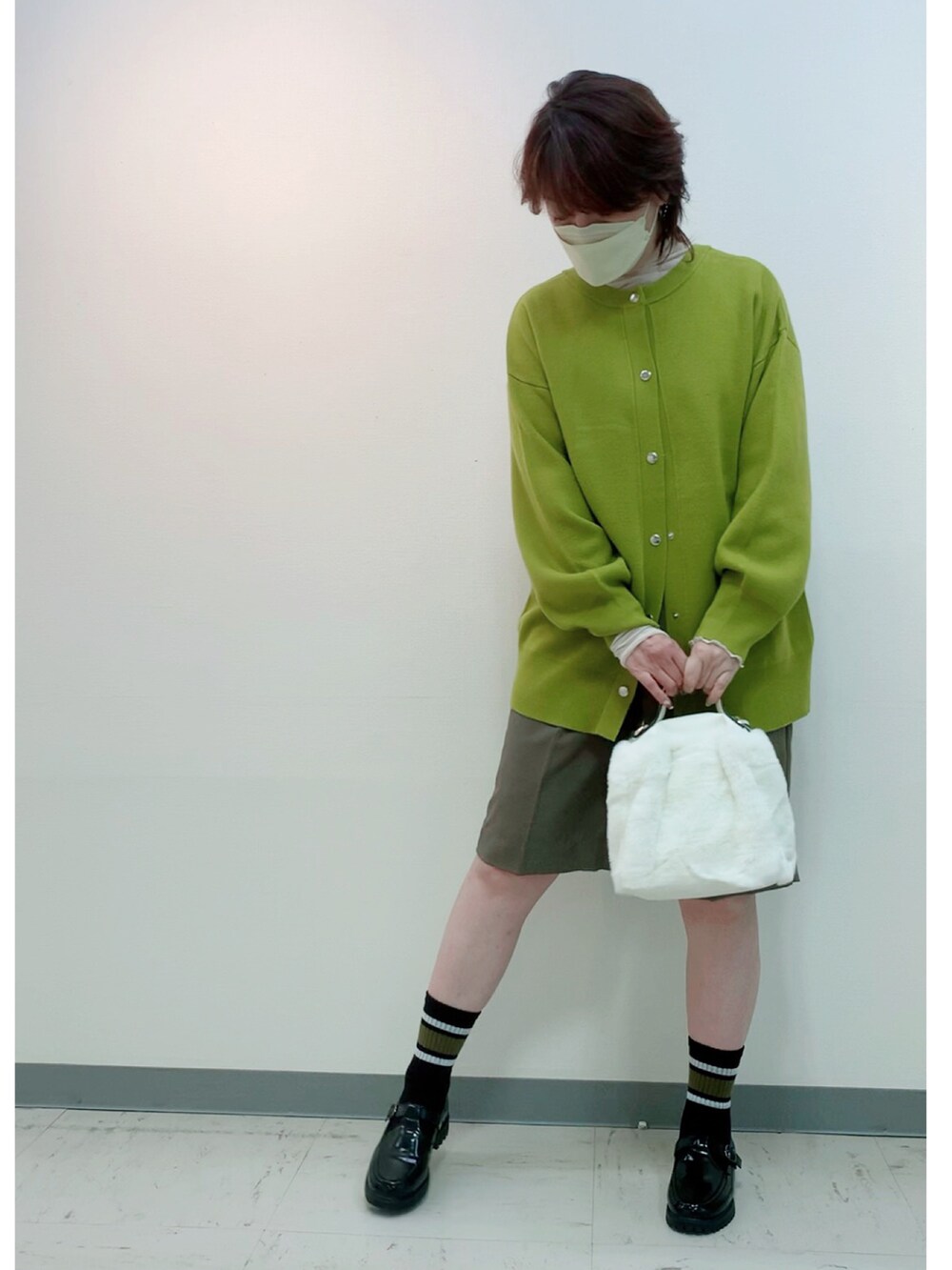 グリーン系のカーディガン/ボレロ、ブラック系のローファー、ホワイト系のバッグを着用したレディースの秋コーディネートの2枚目の写真