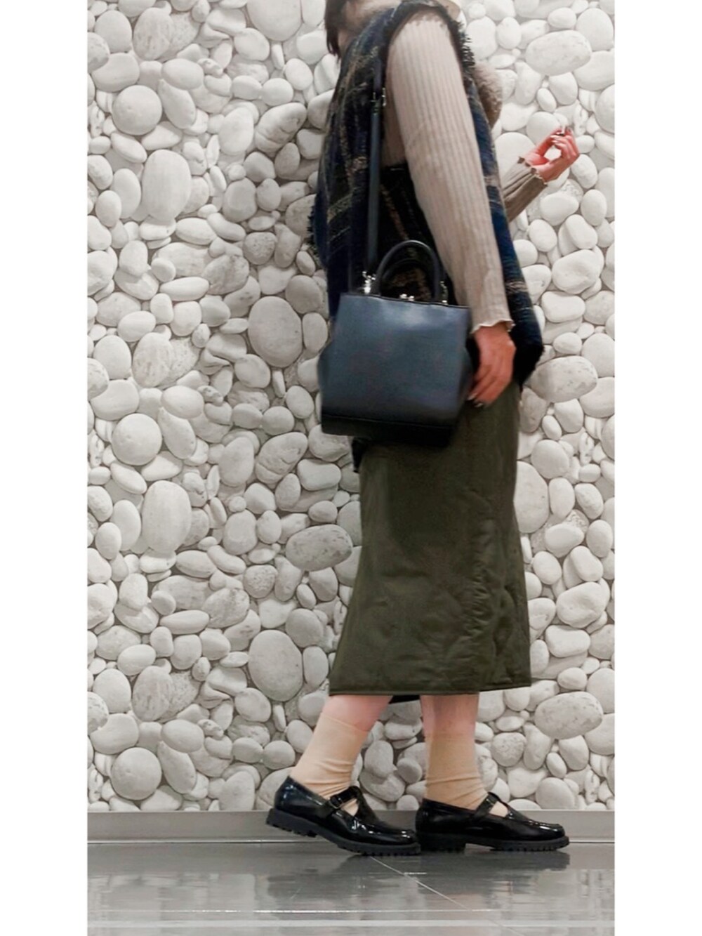 グリーン系のベスト、グリーン系のスカート、ブラック系のローファーを着用したレディースの冬コーディネートの2枚目の写真