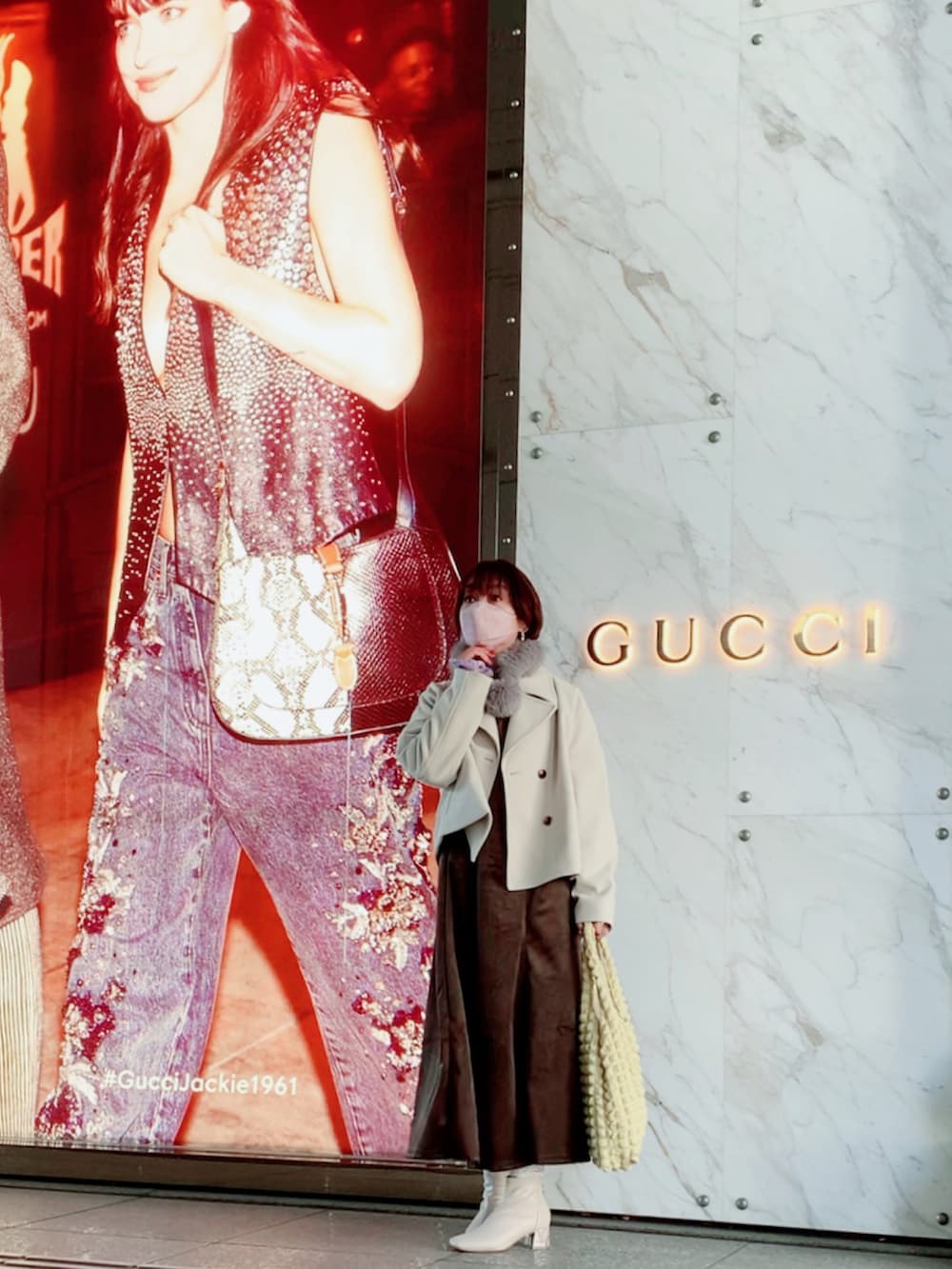 ホワイト系のピーコート、ブラウン系のワンピース、イエロー系のトートバッグを着用したレディースの冬コーディネートの2枚目の写真