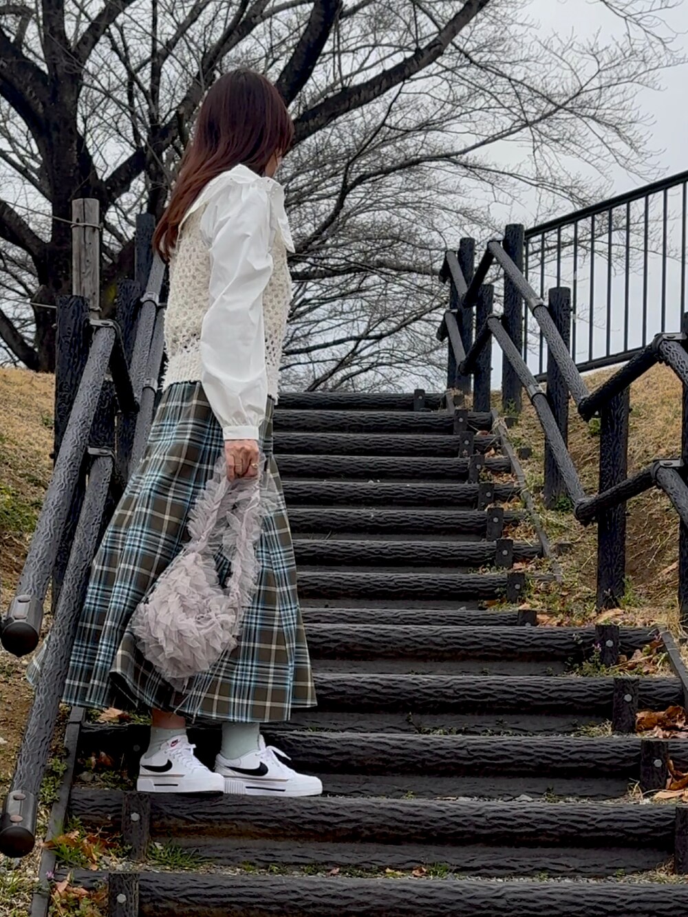 ブルー系のスカート、ホワイト系のスニーカー、グレー系のショルダーバッグを着用したレディースの春コーディネートの2枚目の写真