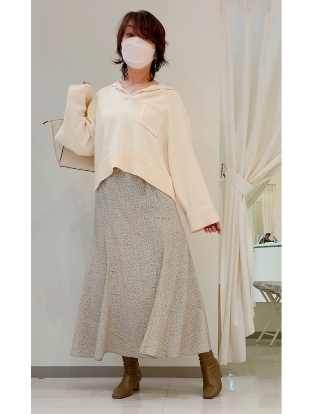 ホワイト系のニット/セーター、ベージュ系のスカート、ブラウン系のブーツを着用したレディースの秋コーディネートの5枚目の写真