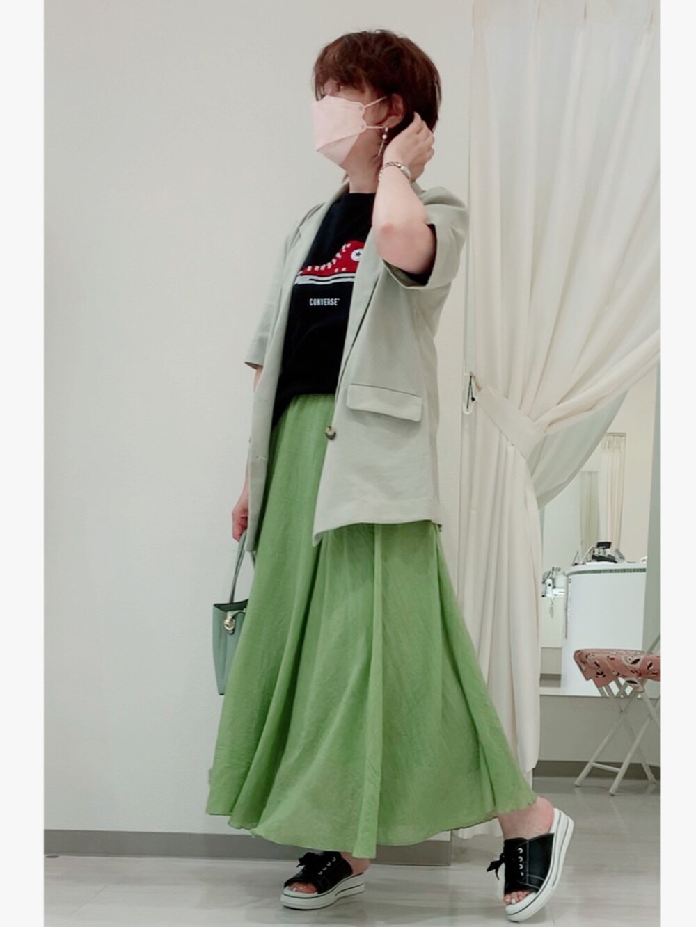 グリーン系のトートバッグ、ブラック系のサンダル、グリーン系のスカートを着用したレディースの夏コーディネートの2枚目の写真