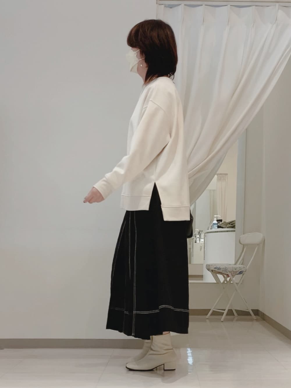 ブラック系のスカート、ホワイト系のブーツ、ホワイト系のTシャツ/カットソーを着用したレディースの秋コーディネートの2枚目の写真