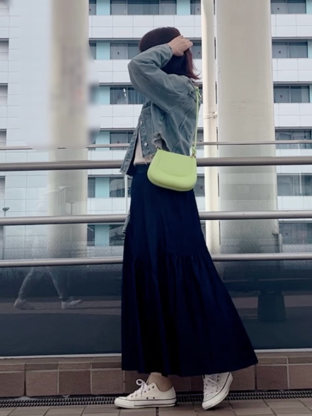 ブルー系のデニムジャケット、ホワイト系のスニーカー、グリーン系のショルダーバッグを着用したレディースの春コーディネートの2枚目の写真