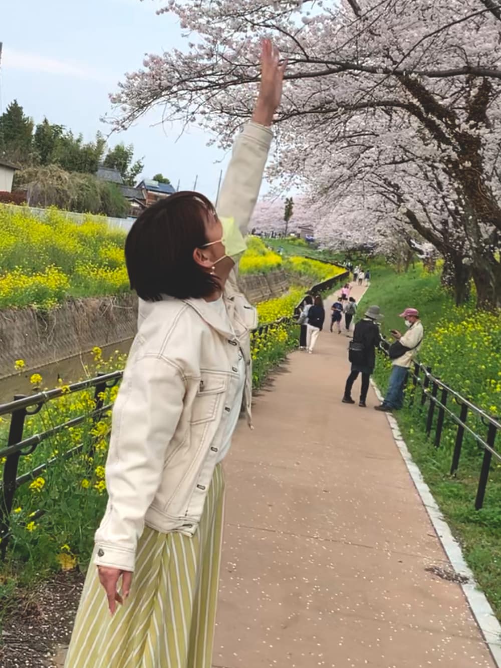 イエロー系のスカート、ブラック系のドレスシューズ、ホワイト系のデニムジャケットを着用したレディースの春コーディネートの2枚目の写真