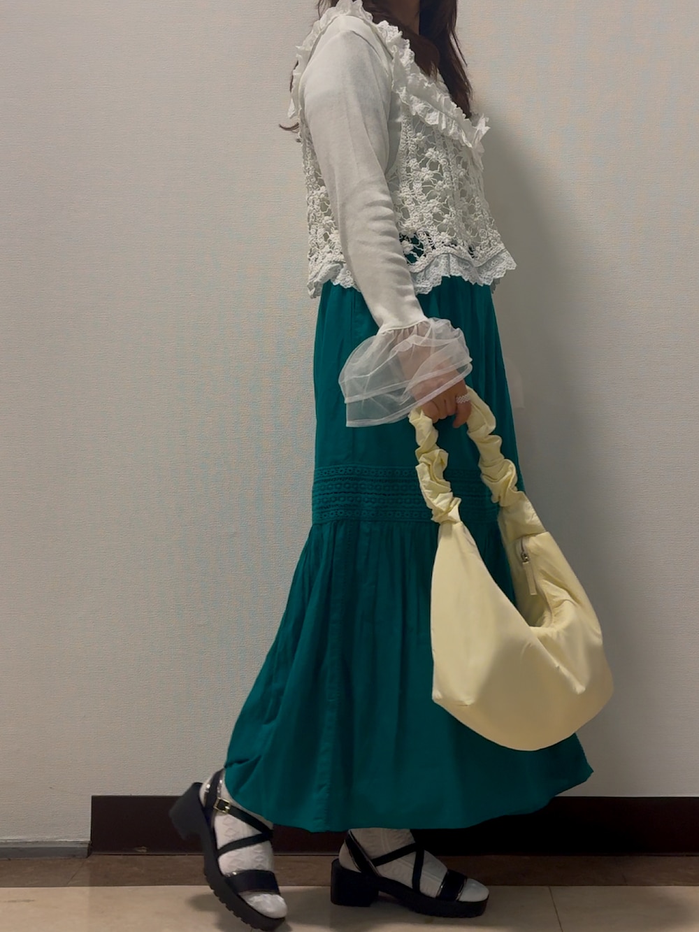 ホワイト系のベスト、ホワイト系のシャツ/ブラウス、グリーン系のスカートを着用したレディースの春コーディネートの2枚目の写真