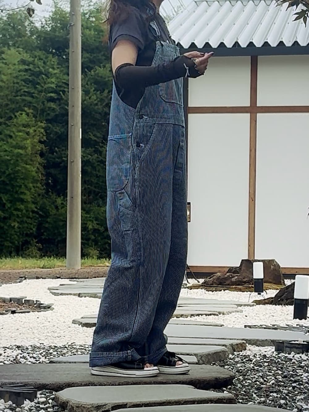 グレー系のTシャツ/カットソー、ブルー系のサロペット/オーバーオール、ブラック系のサンダルを着用したレディースの夏コーディネートの3枚目の写真