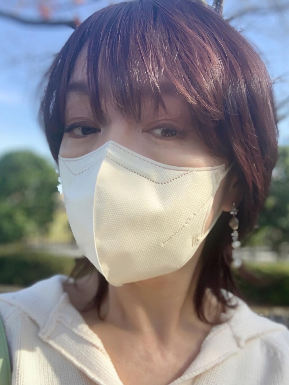 ホワイト系のニット/セーター、ブラウン系のスカート、ブラック系のブーツを着用したレディースの秋コーディネートの2枚目の写真