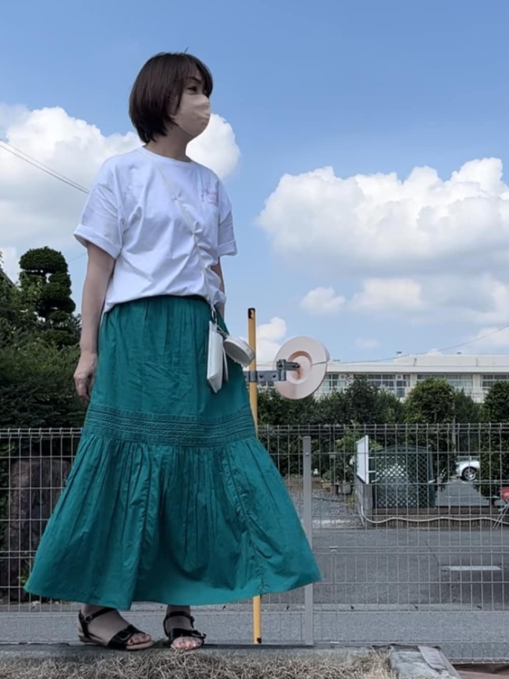 グリーン系のスカート、ホワイト系のチュニック、ホワイト系のボディバッグ/ウエストポーチを着用したレディースの夏コーディネートの3枚目の写真