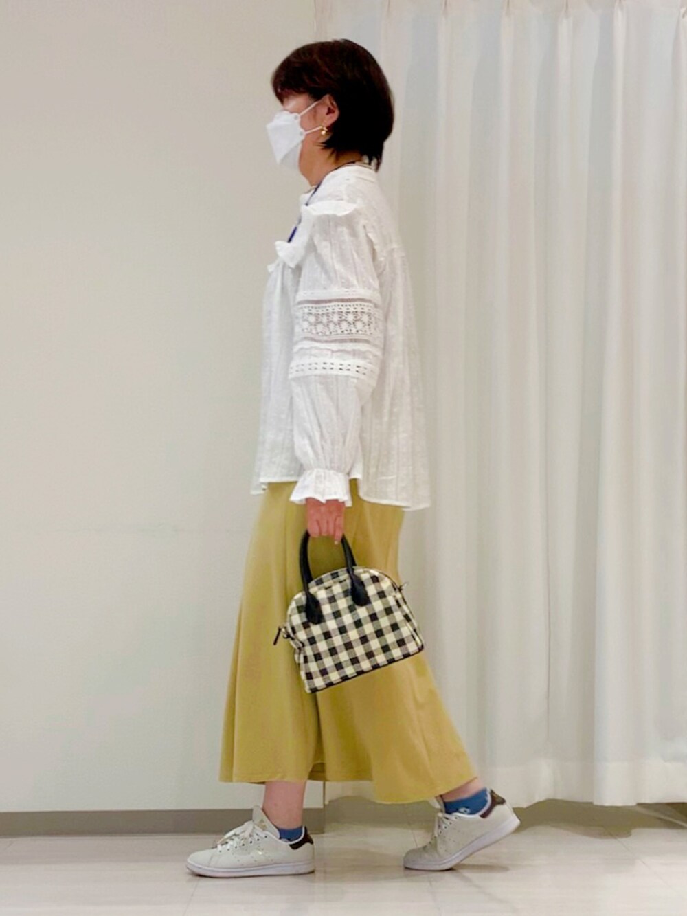 ブラック系のハンドバッグ、ホワイト系のシャツ/ブラウス、イエロー系のスカートを着用したレディースの春コーディネートの3枚目の写真