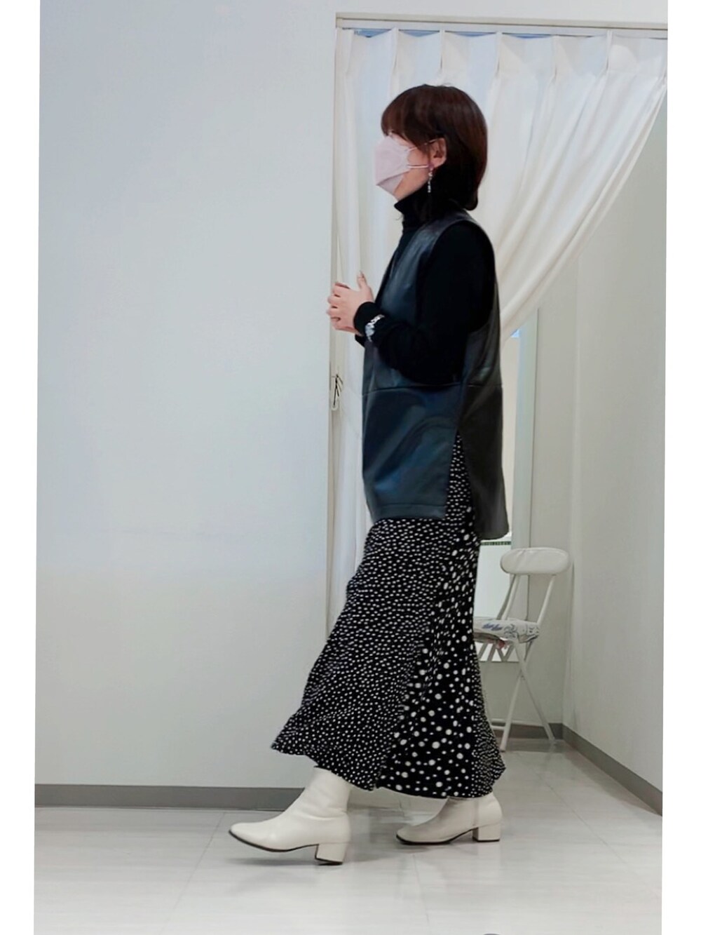 ホワイト系のショルダーバッグ、ブラック系のベスト、ブラック系のスカートを着用したレディースの冬コーディネートの2枚目の写真