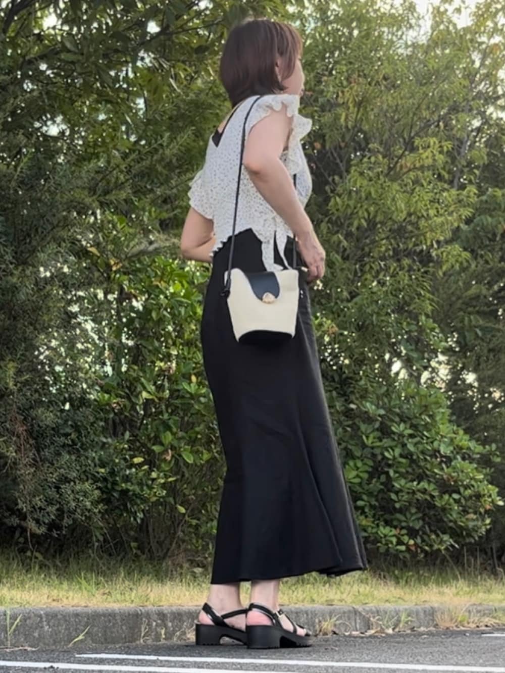 ホワイト系のシャツ/ブラウス、ブラック系のサンダル、ベージュ系のショルダーバッグを着用したレディースの夏コーディネートの2枚目の写真