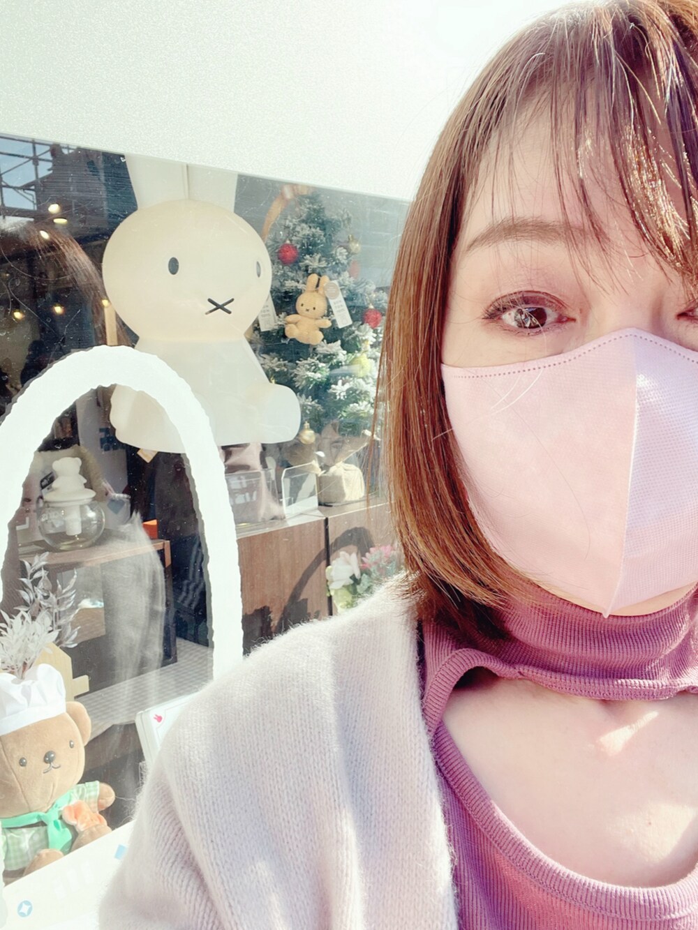 ピンク系のショルダーバッグ、ホワイト系のスカート、ブラック系のブーツを着用したレディースの冬コーディネートの2枚目の写真