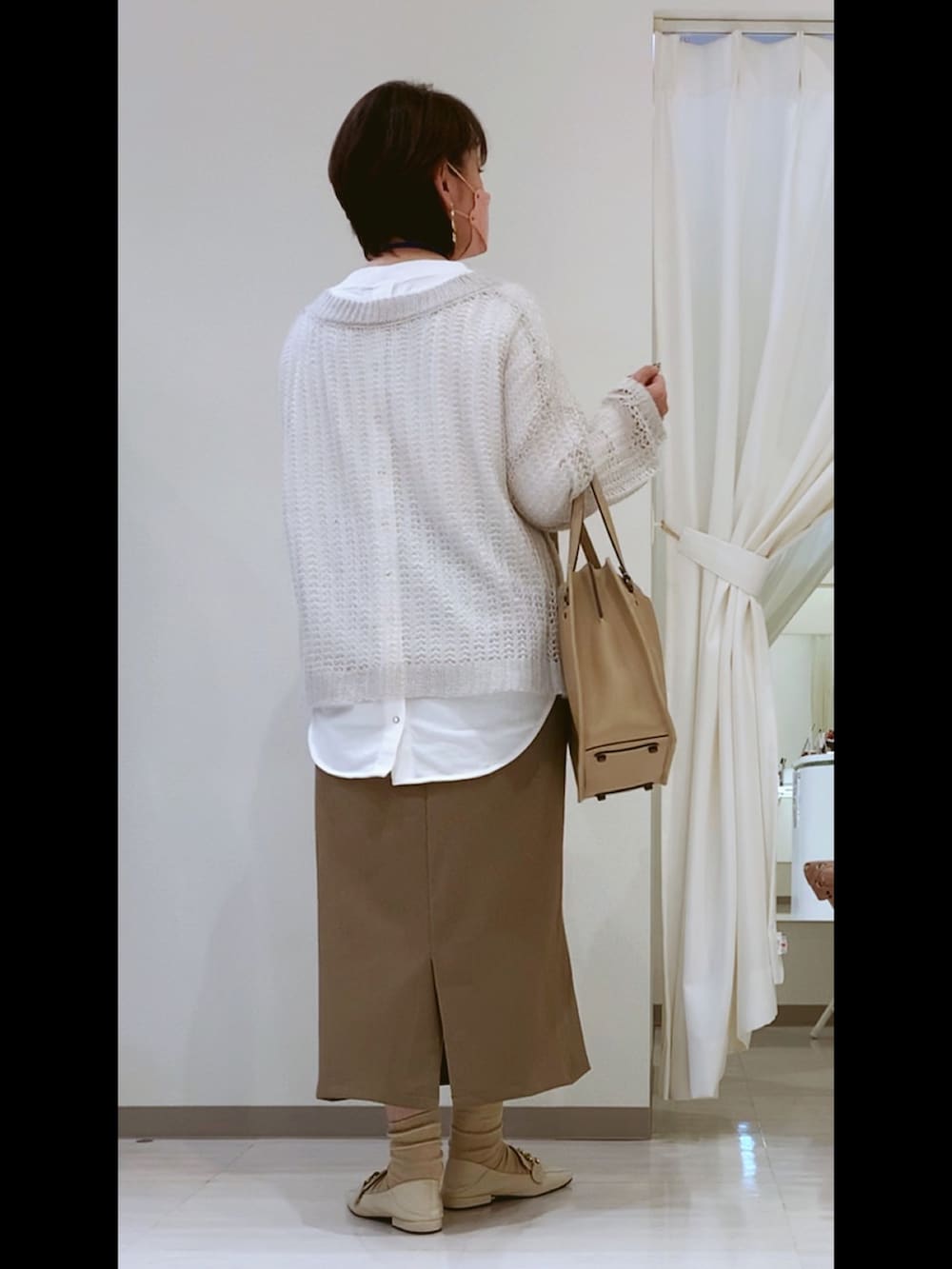 ベージュ系のトートバッグ、ホワイト系のローファー、ブラウン系のスカートを着用したレディースの冬コーディネートの3枚目の写真