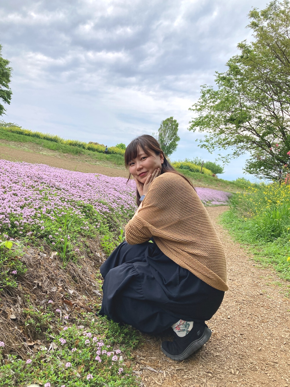 ブラック系のワンピース、オレンジ系のカーディガン/ボレロを着用したレディースの春コーディネートの2枚目の写真