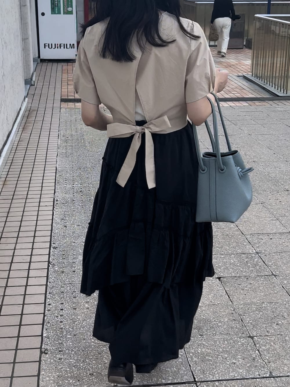 ベージュ系のシャツ/ブラウス、ブラック系のスカート、ブルー系のハンドバッグを着用したレディースの秋コーディネートの2枚目の写真