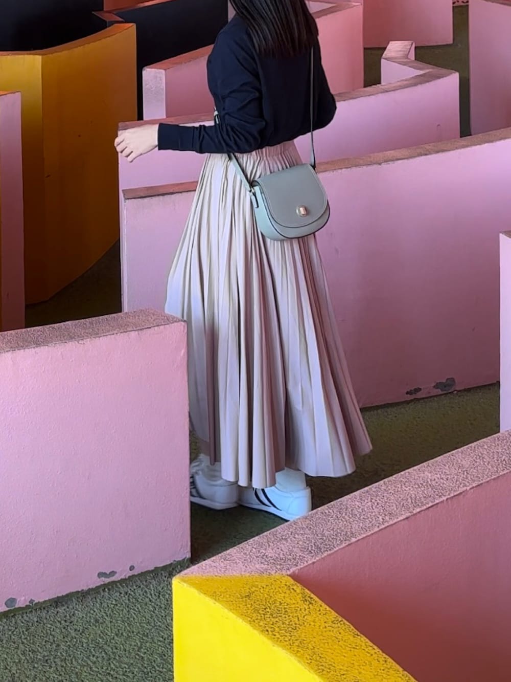 ピンク系のスカート、ブラック系のカーディガン/ボレロ、ホワイト系のスニーカーを着用したレディースの秋コーディネートの2枚目の写真