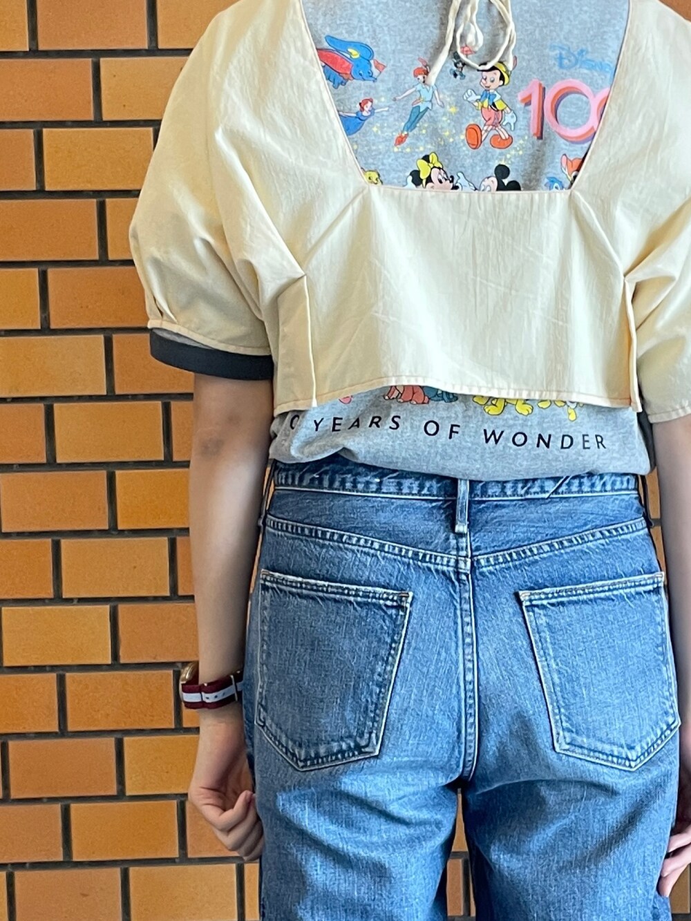 ベージュ系のシャツ/ブラウス、グレー系のTシャツ/カットソー、ブルー系のデニムパンツを着用したレディースの春コーディネートの2枚目の写真